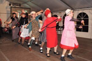 Gruppe von Frauen in traditionellen Kostümen tanzen mit Besen
