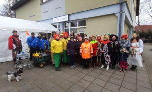 Ein Gruppe von Menschen in verschiedenen Kostümen. Ein Mann und eine Frau jeweils am Ende der Gruppe.