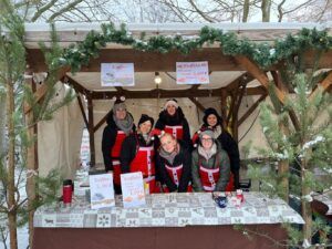 Gruppe von Menschen in roten Schürzen am Weihnachtsstand