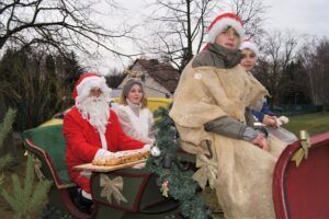 Ein Weihnachtsmann und drei Personen im Schlitten